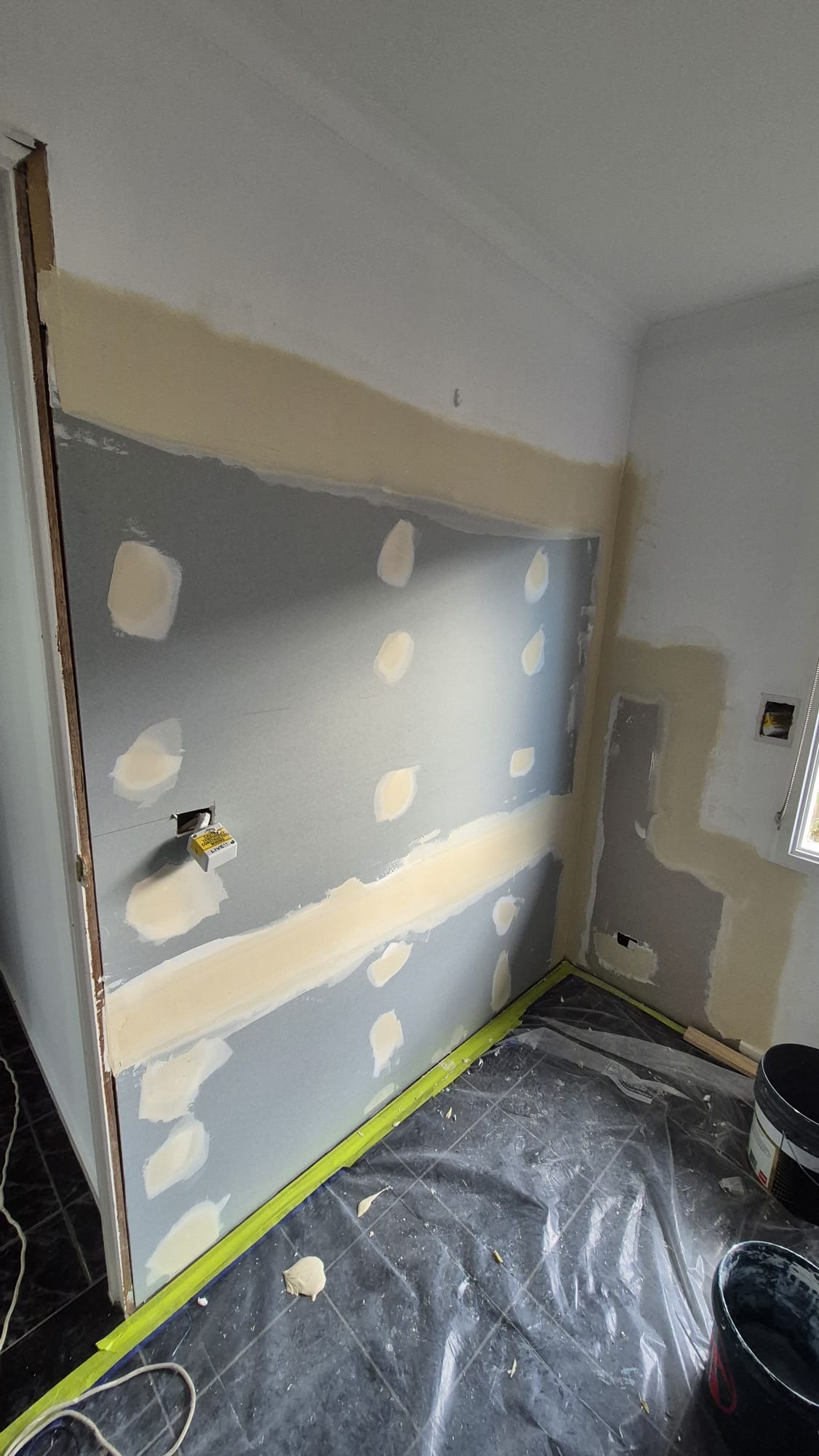 Interior wall with fresh plaster patching and taped edges before painting